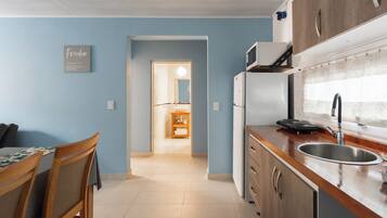 Cocina pequeña con refrigerador, microondas y pileta.
