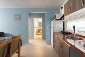 Cocina pequeña con refrigerador, microondas y pileta.