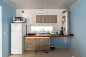 Een praktische keuken met een koelkast, magnetron, spoelbak en een boiler.
