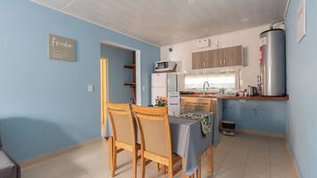 Cocina compacta con comedor, que incluye microondas, refrigerador, lavamanos y calentador de agua.