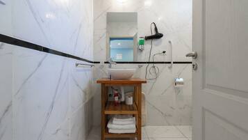 Un baño con piso de mármol, tocador de madera con lavamanos y un perchero.