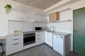 Eine moderne Küche mit weißen Schränken, einer Mikrowelle, einem Backofen und einem Geschirrspüler.