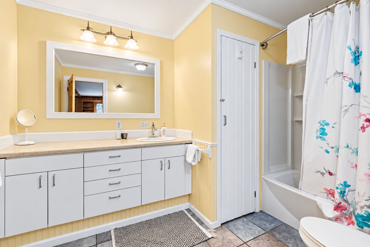 A bathroom with a sink, mirror, and shower curtain.