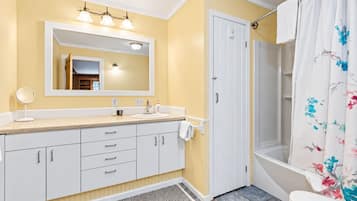 A bathroom with a sink, mirror, and shower curtain.