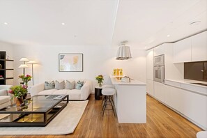 A modern living room with a sofa, coffee table, and a painting on the wall. - Fitzrovia 3-bed Central AC Concierge (London)