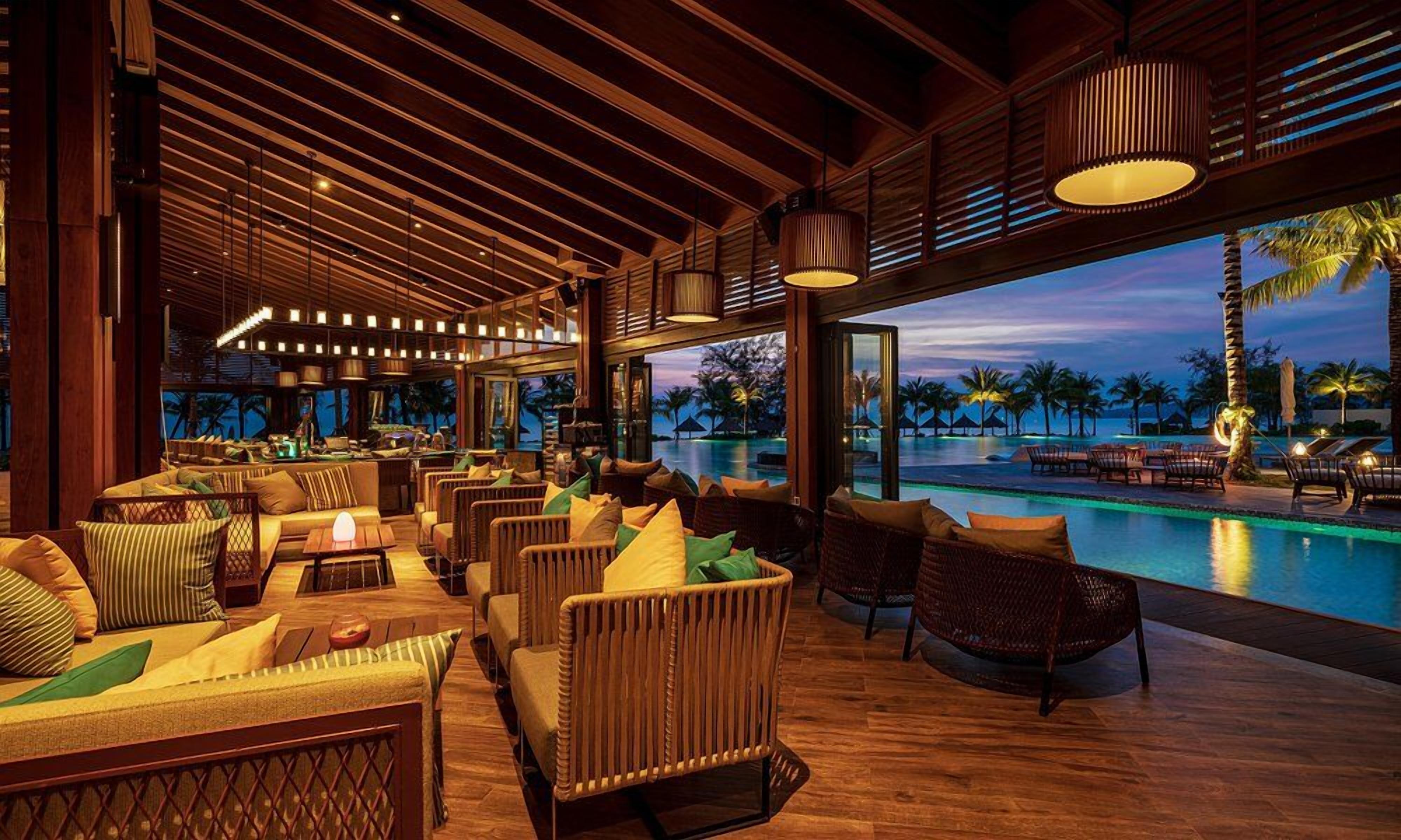 Un espacio interior bien iluminado con disposición de asientos, vista a la piscina y zona de bar.