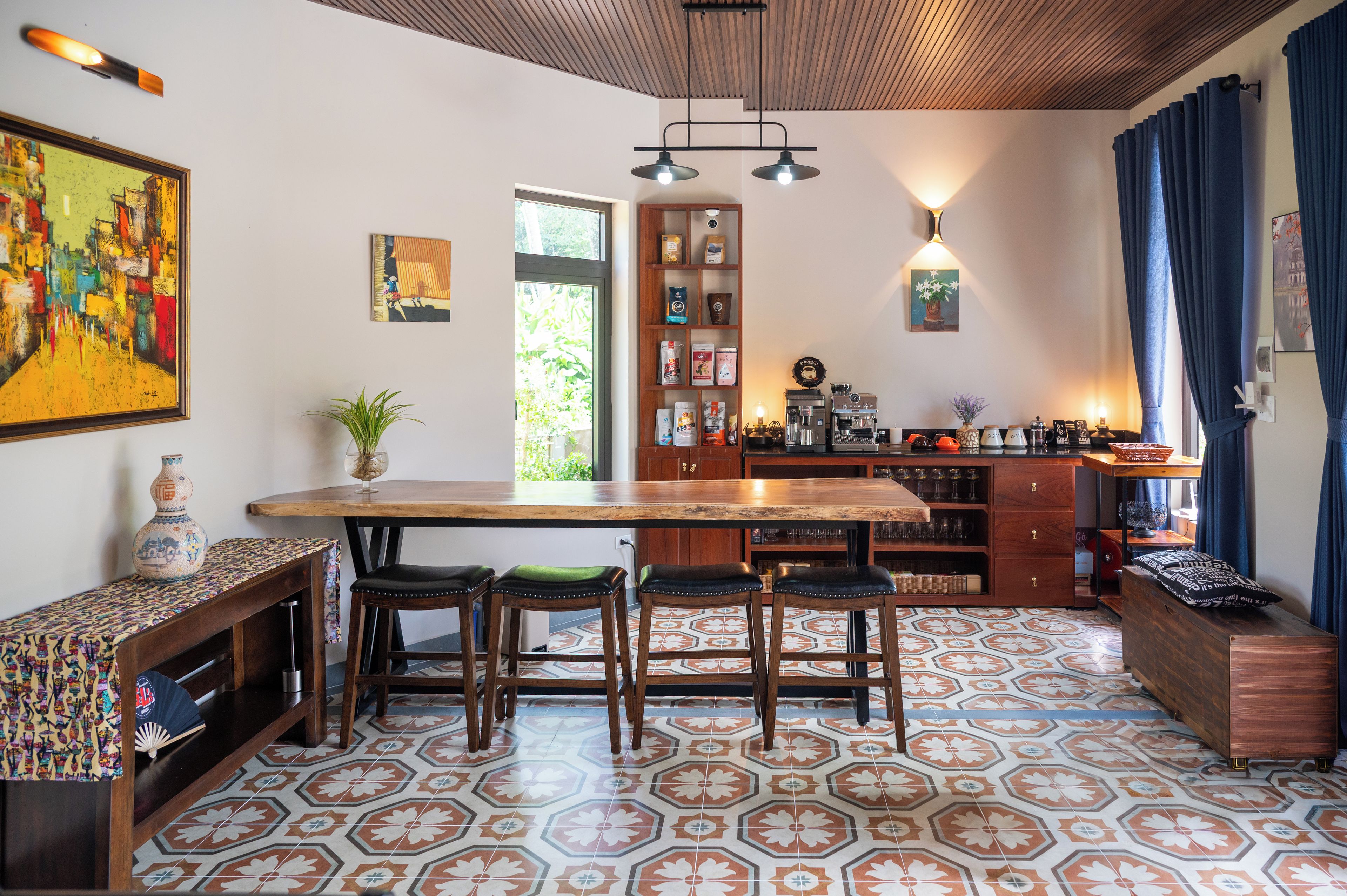 A kitchen with a wooden bar, stools, a coffee machine, and a variety of kitchen items.