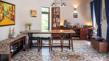 A kitchen with a wooden bar, stools, a coffee machine, and a variety of kitchen items.