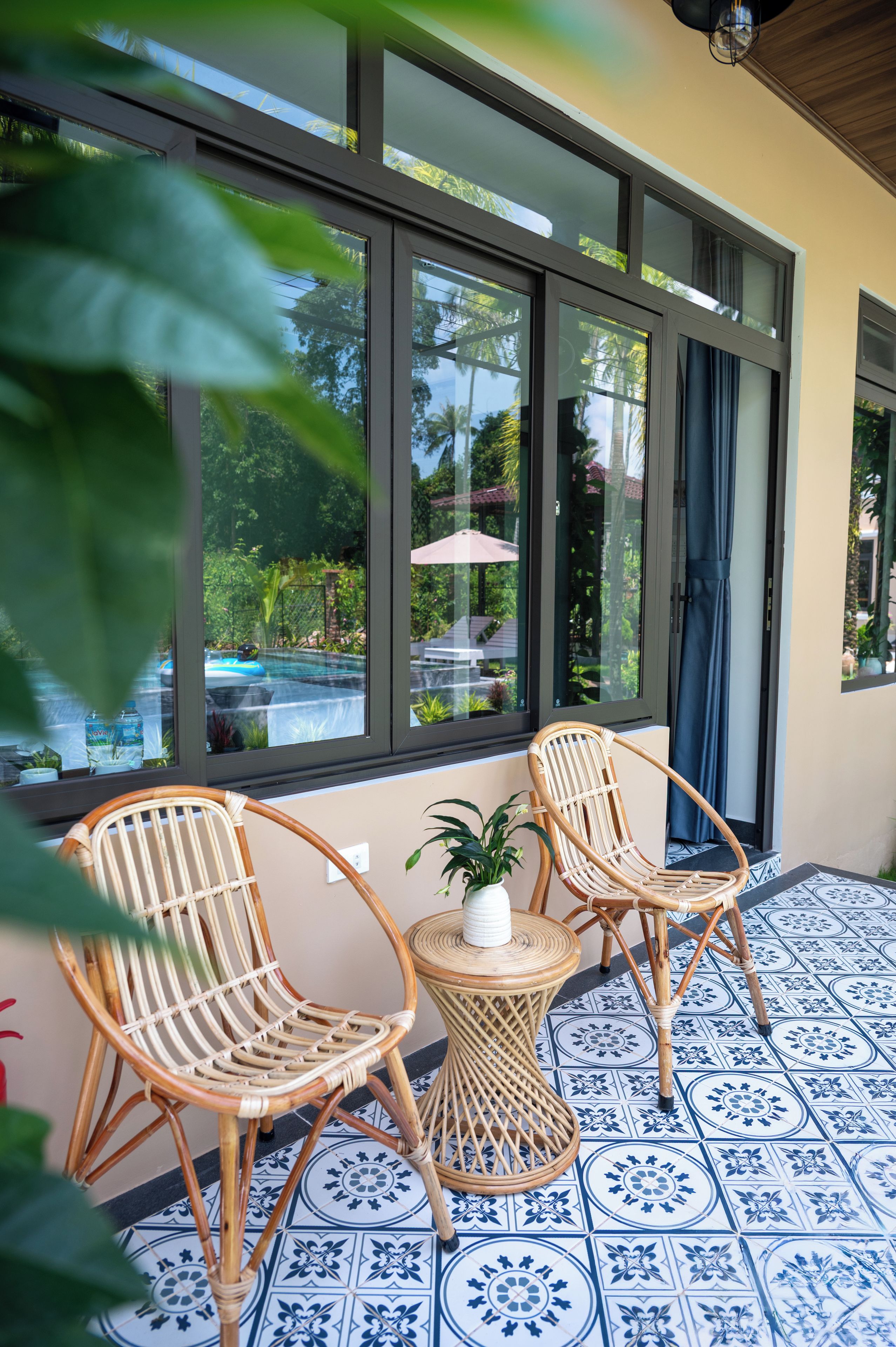 A room with two wicker chairs, a small round table, and a potted plant.
