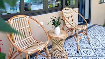 A room with two wicker chairs, a small round table, and a potted plant.