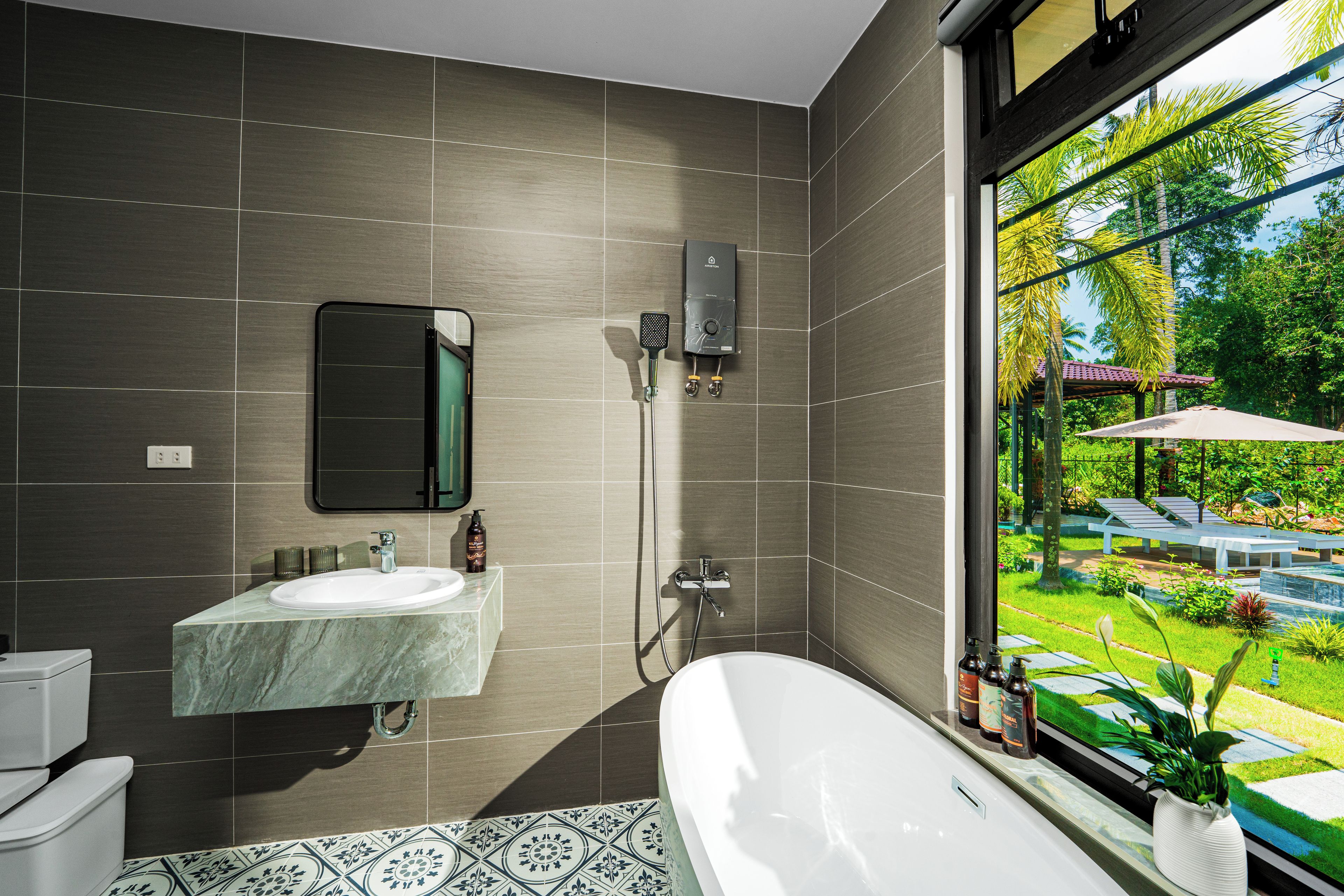 Un baño moderno con una bañera grande, una zona de ducha independiente y un ventanal con vistas a un jardín.