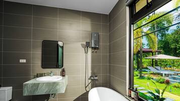 Un baño moderno con una bañera grande, una zona de ducha independiente y un ventanal con vistas a un jardín.
