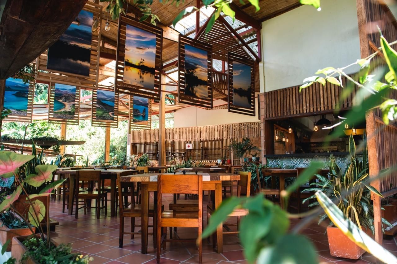 Un restaurante con mobiliario de madera, separadores de bambú y obras de arte en las paredes.
