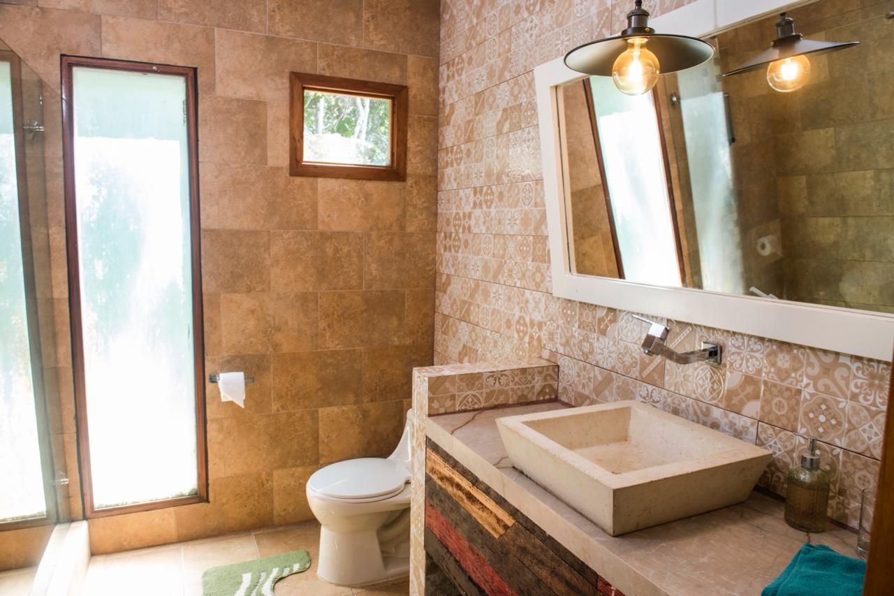 Un baño con inodoro, lavamanos y zona de ducha.