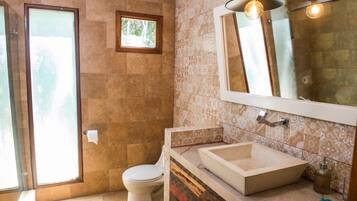 Un baño con inodoro, lavamanos y zona de ducha.