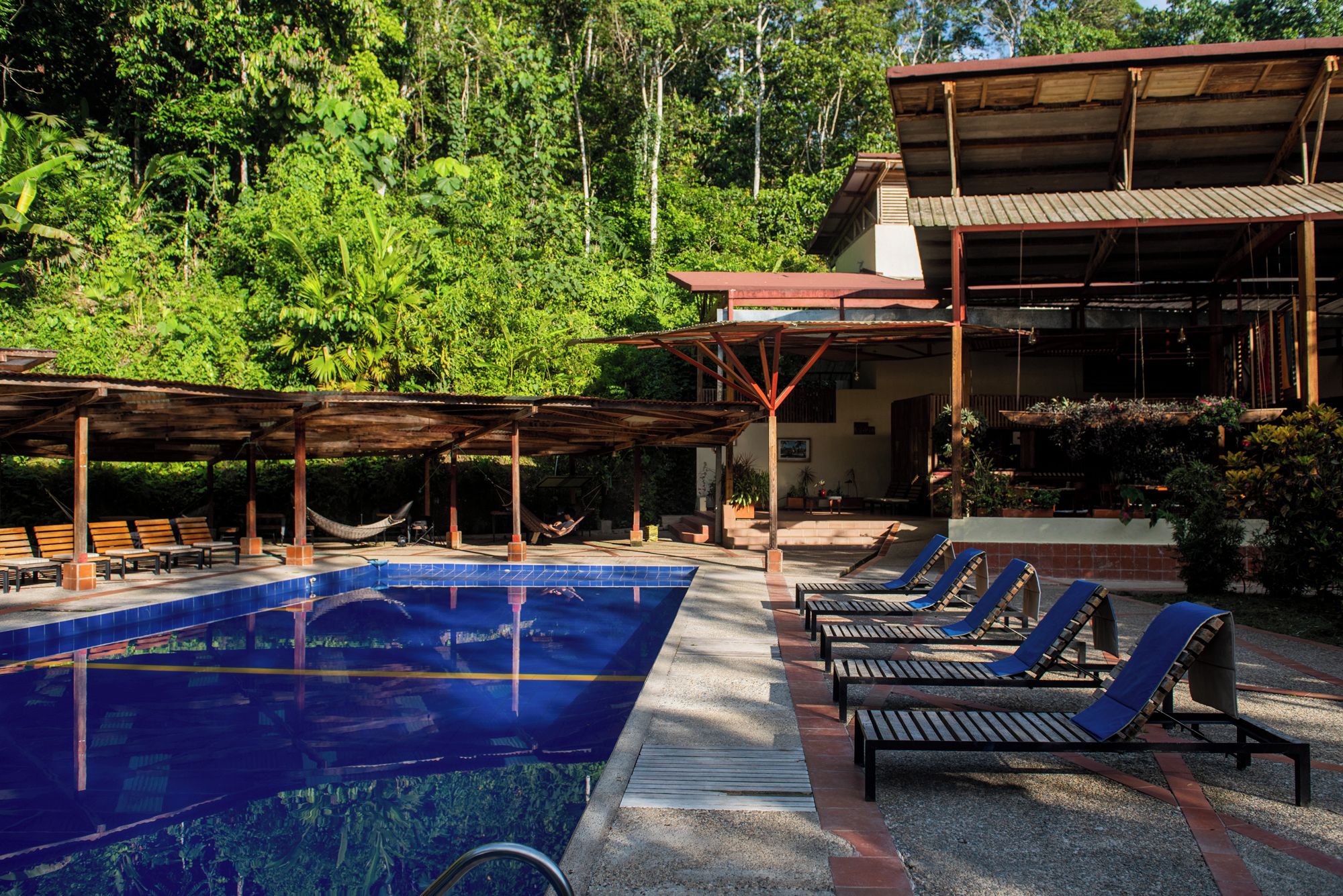 Un espace piscine avec des chaises longues et un coin salon abrité.