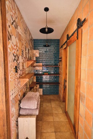 A narrow hallway with patterned walls, a wooden bench, and a hanging light fixture. - Itamandi Eco Lodge (Ahuano)