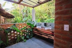 A bathroom with two sinks, a wooden bench, and a brick wall.