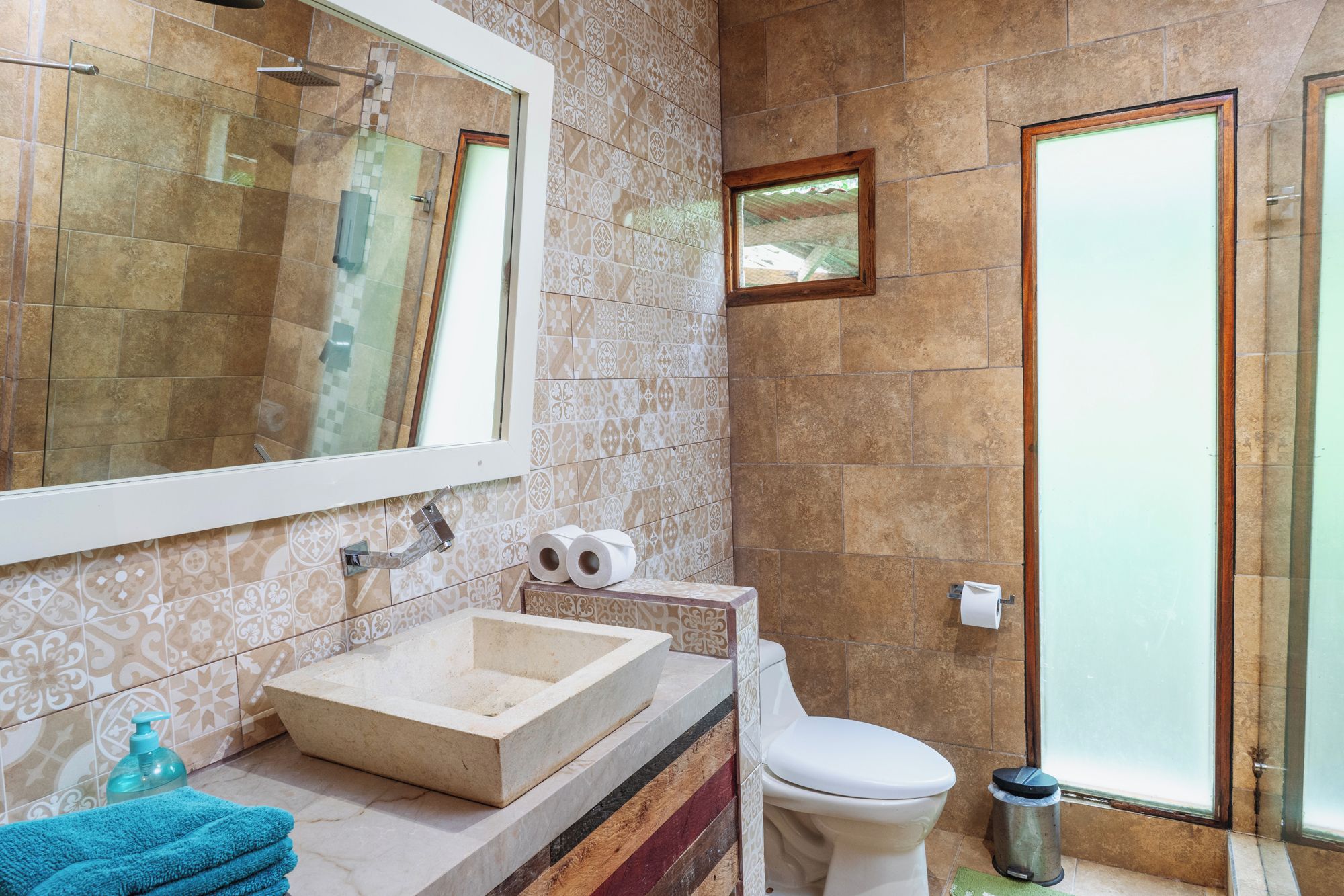 Un baño con un espejo grande, un lavamanos, inodoro y ducha.