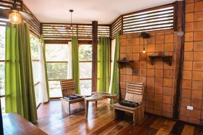 A room with wooden flooring, a wooden bench, a small table, and a hanging light fixture.
