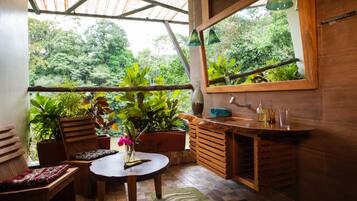 Un interior de madera con una mesa redonda, sillas, un banco, un lavabo y un espejo.