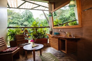 A wooden interior with a round table, chairs, a bench, a sink, and a mirror.