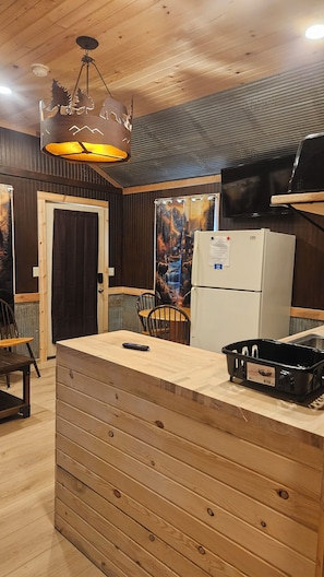 A compact kitchen with a wooden counter, a refrigerator, and a microwave.