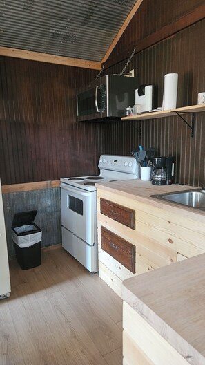 A compact kitchen with a stove, microwave, and a coffee maker on the counter.