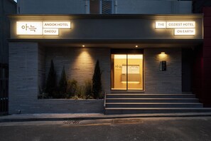Una entrada de hotel con señalización iluminada para Anook Hotel Daegu y El Hotel Más Acogedor del Mundo.