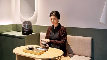 A person seated at a round table with a bowl and a book, in a room with a green accent wall and a modern design.