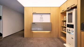 Un área de recepción con mostrador de madera, quiosco de auto-registro y una baraja de cartas.