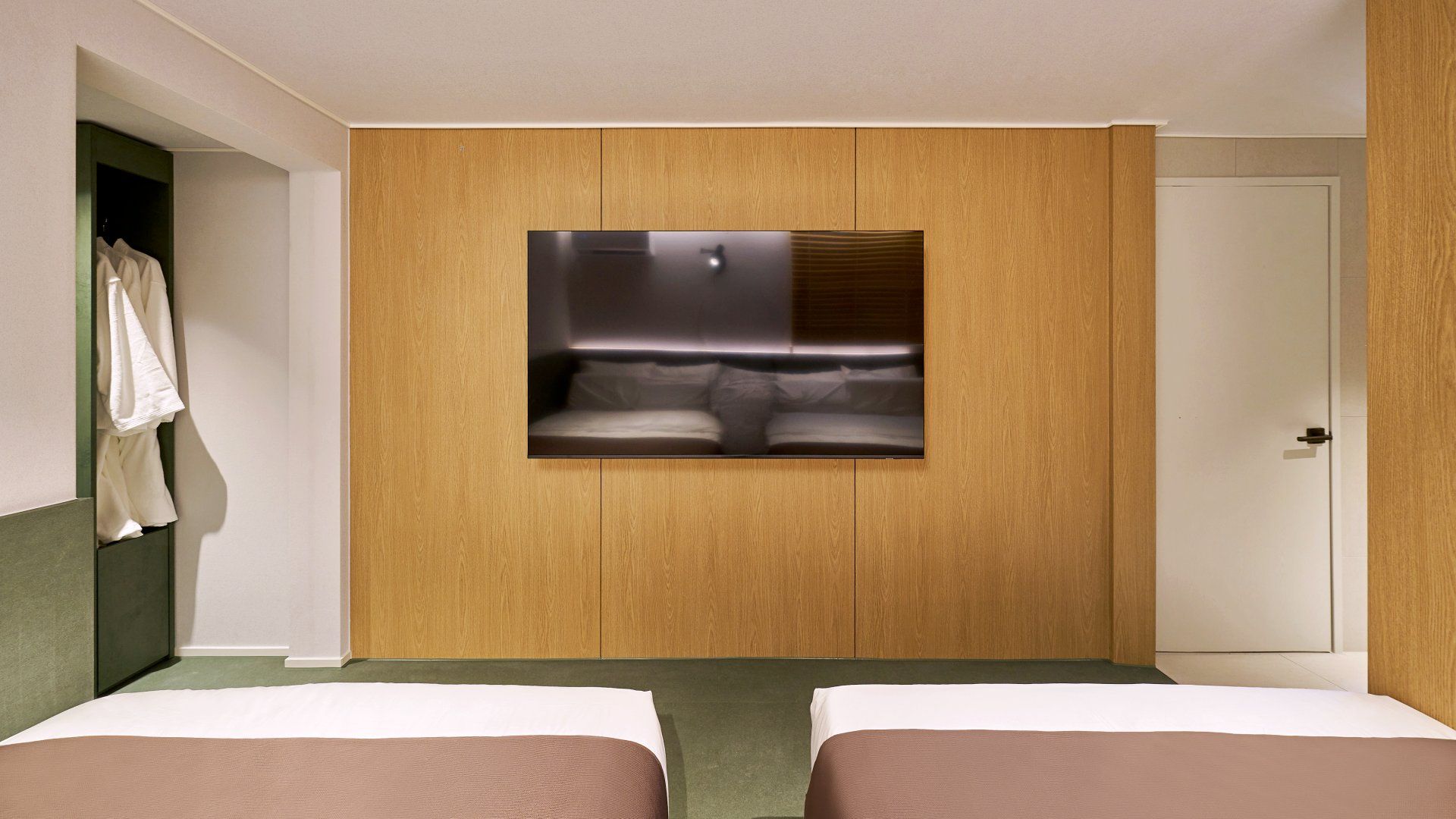 A hotel room with two beds, a built-in wardrobe, and a mirror.