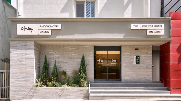 A hotel entrance with signage for 'ANOOK HOTEL' and 'THE COZIEST HOTEL ON EARTH'.