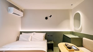 A hotel room with a bed, bedside table, lamp, and a small seating area with a table and chairs. - Anook Hotel Daegu Station (Daegu)