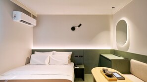 A hotel room with a bed, bedside table, lamp, and a small seating area with a table and chairs. - Anook Hotel Daegu Station (Daegu)