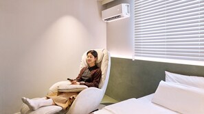 Una habitación con sillón de masajes, cama y ventana con persianas.
