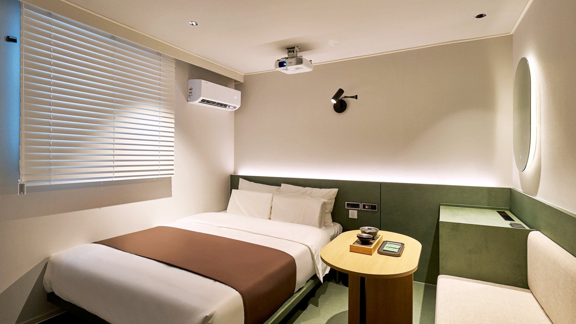A hotel room with a bed, bedside table, and a small seating area.