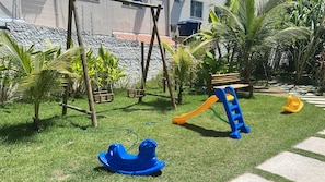 Ein Spielplatz mit Rutsche, Schaukeln und einer Kletterkonstruktion.