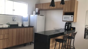 Eine moderne Küche mit Holdekor, einer schwarzen Arbeitsplatte, einem Kühlschrank, einer Kaffeemaschine und einer Mikrowelle.