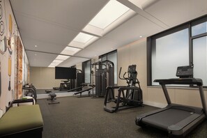 Et fitnesscenter med forskellig træningsudstyr, herunder løbebånd og vægtmaskiner.