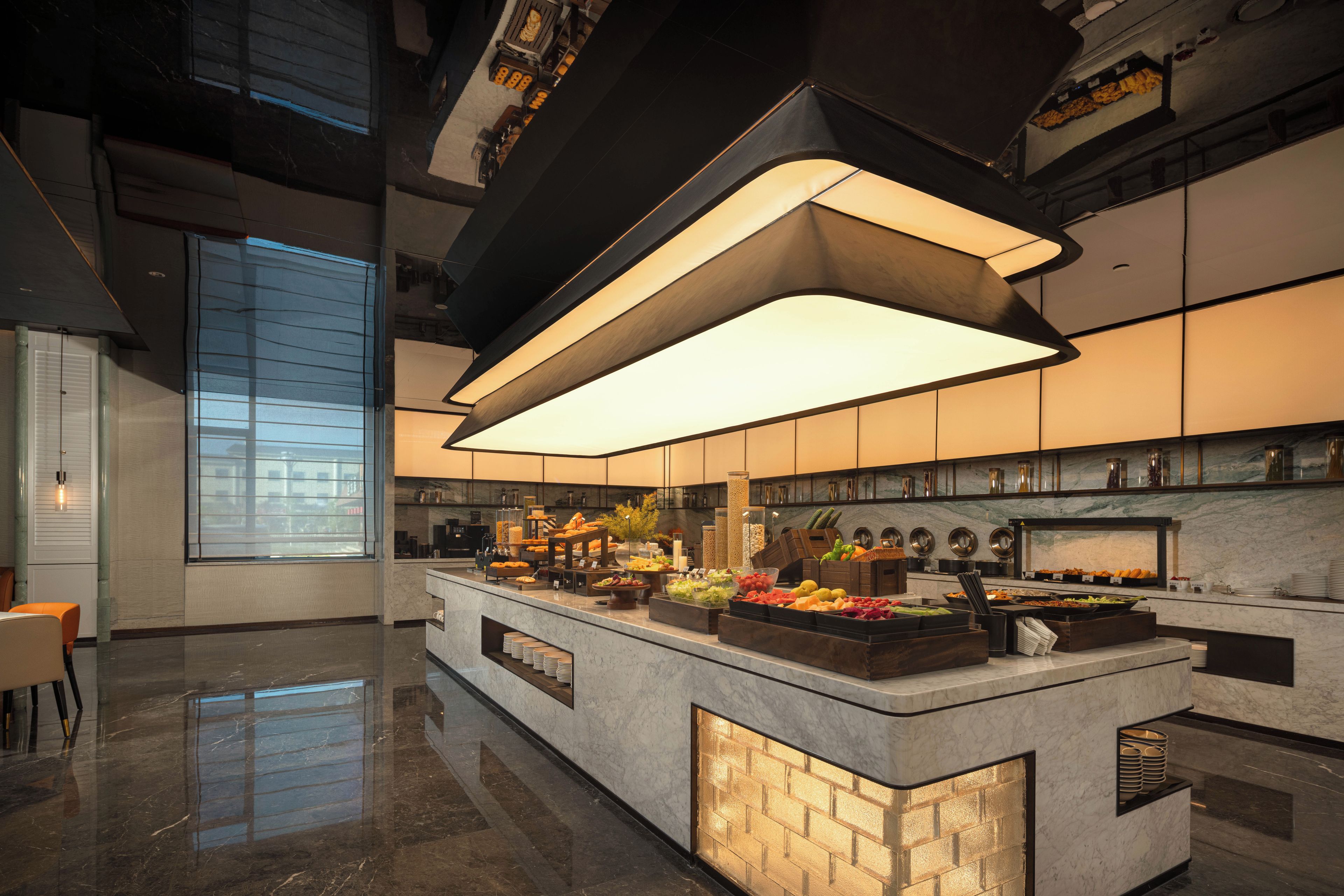 Una cocina moderna con una isla central, encimeras de mármol y una lámpara colgante grande.