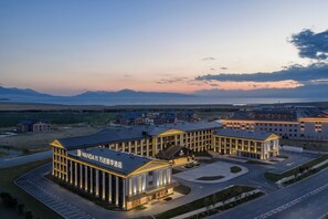 Un complexe hôtelier moderne composé de plusieurs bâtiments, doté d’un parking et offrant une vue sur les montagnes en arrière-plan.