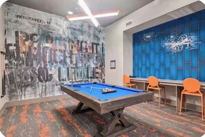 Een biljarttafel in een ruimte met een muur vol graffiti en een blauw patroon.