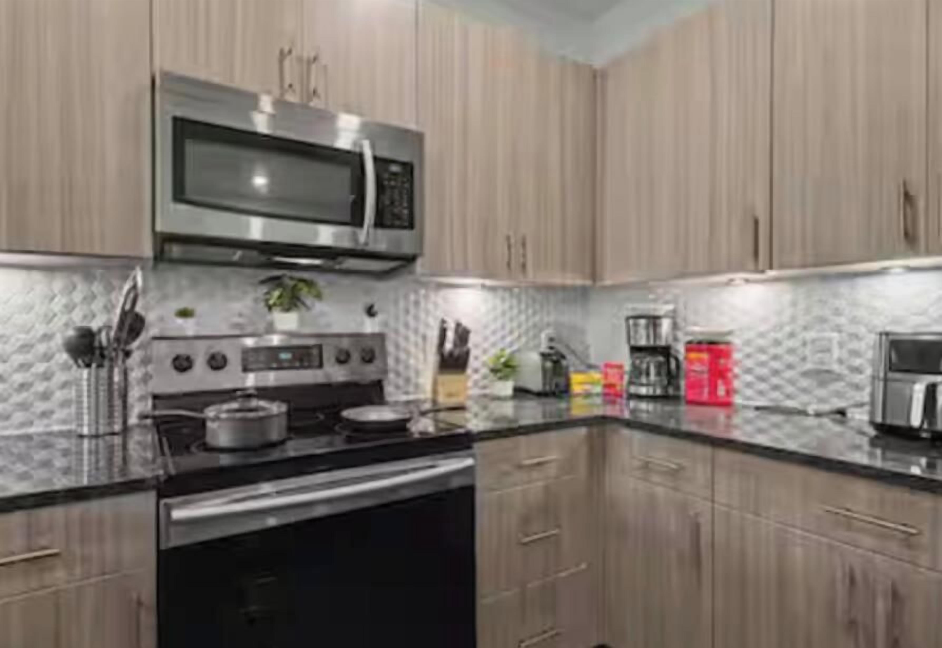 A modern kitchen with stainless steel appliances, wooden cabinets, and a granite countertop.