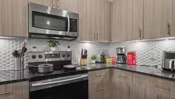 A modern kitchen with stainless steel appliances, wooden cabinets, and a granite countertop.