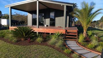 A modern house with a covered patio, a paved walkway, and a variety of plants.