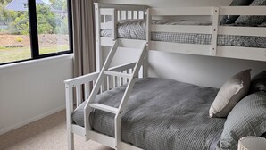 Een stapelbed met uitzicht op een huis en tuin door een raam.