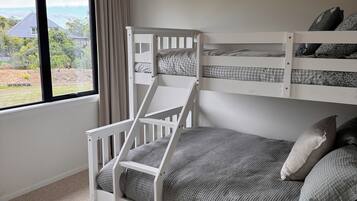 A bunk bed with a view of a house and garden through a window.