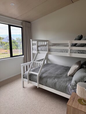 A bunk bed with a view of a house and garden through a window. - WAINUI SUNSET HIDEAWAY
WHERE EVERY EVENING ENDS WITH A BEAUTIFUL SUNSET (Gisborne)