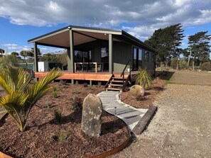 Una casa moderna con un porche cubierto, mobiliario exterior y un jardín ajardinado.